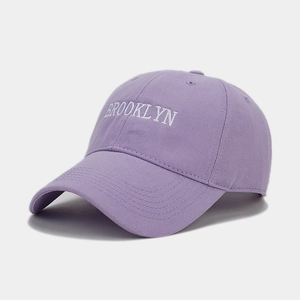Close-up of white Brooklyn embroidery on a purple cotton twill baseball cap with curved brim