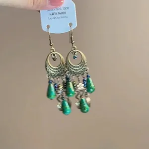 Macro detail of ethnic drop earrings with green beads and gold filigree on a silver hook