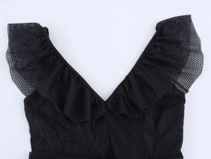 Close-up of elegant black mesh fabric featuring ruffle details and V-neckline texture