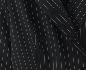 Gros plan sur le tissu à rayures du blazer noir et blanc avec détail d'un bouton noir