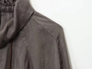 Detail of taupe bomber jacket featuring ribbed collar and woven drawstring texture