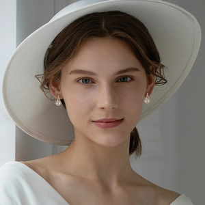 Detailed close-up of a faux pearl earring with a pavé-set V-shape on a female model