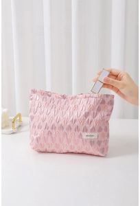 Pink heart embossed canvas makeup bag showing interior storage for lipstick and items