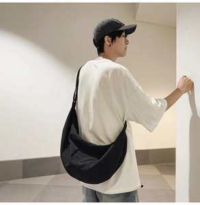 Vue latérale d'un mannequin portant un grand sac bandoulière en nylon noir de style décontracté