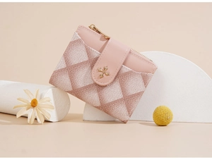Detail shot of pink and white quilted short wallet with gold buckle and zip