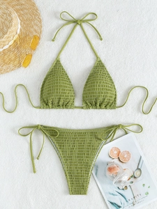 Detail of green smocked halter bikini with side-tie bottoms on soft white background