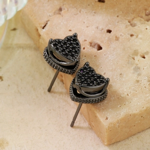 Minimalist copper heart stud earrings with black pavé zircons on natural stone background