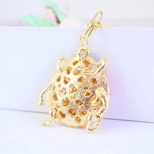Golden beetle keychain with hollow heart patterns on polished metal surface