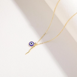 Macro detail of gold-plated evil eye and cornicello chili charms on a sleek chain