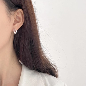 Close-up of a model wearing a minimalist silver U-shaped earring with a polished finish