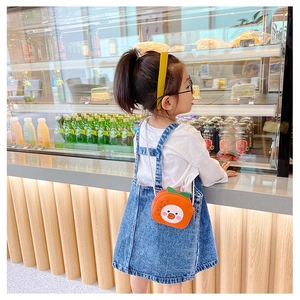 Detail of cute orange fruit-shaped crossbody bag worn by a young child model