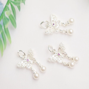 Macro detail of silver hollow bow pendant with pearls and purple gemstones for jewelry making