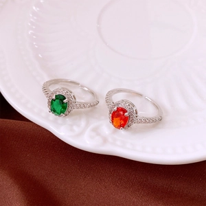 Close-up of adjustable silver rings with oval emerald green and ruby red zircon stones