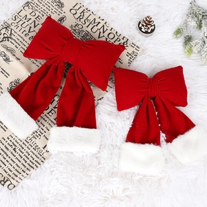 Large red velvet Christmas bows with white faux fur trim set on snowy pine background