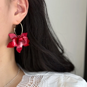 Detail shot of red resin flower earring with gold hoop on a model wearing lace