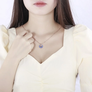 Rose gold zodiac Ox necklace with blue enamel pendant worn on a female model neck