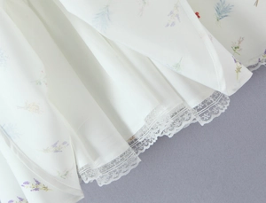 Dettaglio dell'orlo del vestito a fiori bianco con pizzo delicato e tessuto leggero