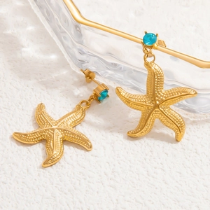 Detail of 18k gold starfish earrings with blue zircon stone on a white background