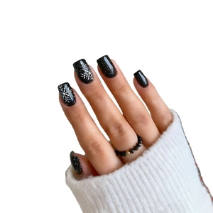 Winter press-on nails with black glitter finish and white snowflake festive nail art