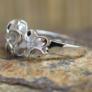 Minimalist silver peach blossom flower ring with clear zircon on natural stone background