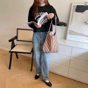 Detail of a brown striped knit tote bag styled with a black hoodie and light blue jeans