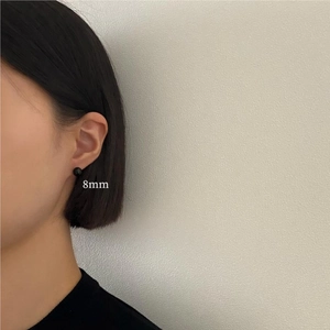 Close-up of 8mm black onyx stud earring shown on a model for actual size reference