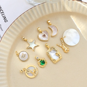 Assorted gold-plated mother of pearl pendants in heart, moon and star shapes on a plate