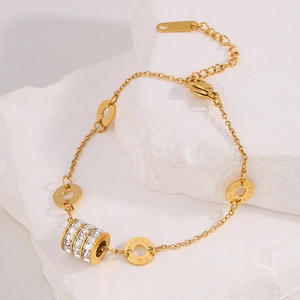 Detail of gold bracelet with roman numerals charm and sparkling zircon stones on stone