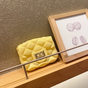 Mini bolso bandolera amarillo con diseño acolchado y cadena dorada en estante