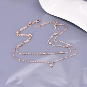 Double-layered rose gold stainless steel necklace with metal beads and a crystal pendant