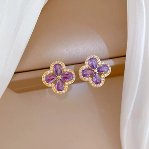 Macro shot of gold clover earrings with purple amethyst and shimmering cubic zirconia