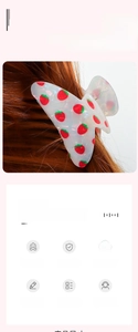 Close-up of a white acrylic hair claw clip with red strawberry patterns on brown hair