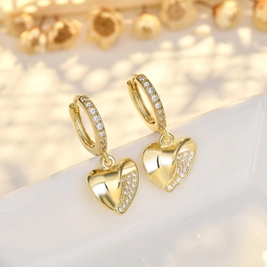 Elegant gold heart earrings with zircon inlay on a white porcelain display base