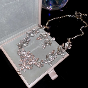 Detailed macro of flower leaf necklace set with pink crystals on black velvet display box