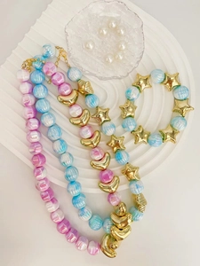 Primo piano di collane e bracciale di perle color caramella con stelle dorate