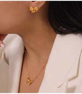 Detailansicht der eleganten Gold-Schleifen-Halskette und passenden Ohrstecker am Model