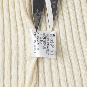 Close-up of cream white ribbed knit fabric with white wash care label and garment details