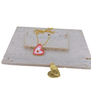 Gold-plated necklace with layered pink enamel heart pendant on a stone display