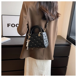 Quilted black crossbody bag with star rivets and pearl bow shown on model's shoulder