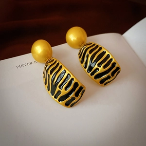 Close-up of vintage gold stud earrings with black zebra pattern enamel on a book