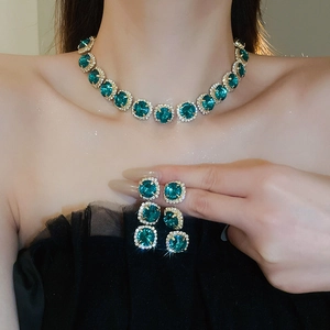 Detail of emerald green crystal necklace and earrings set on a model with gold finish