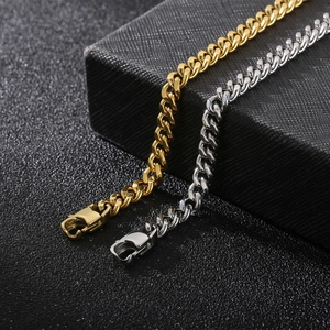 Detail of silver and gold Cuban link chains with lobster clasps on a black jewelry box