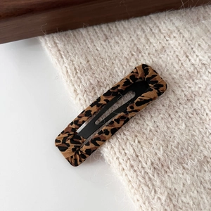 Detailed view of rectangle leopard print hair clip on a minimalist textured surface