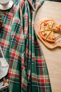 Detailed close-up of green plaid cotton blend fabric draped on a rustic wooden table