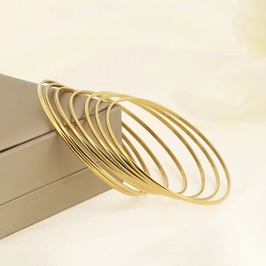 Minimalist stackable gold layered stainless steel bracelets set on elegant jewelry box