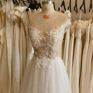 Elegant white lace wedding dress with 3D floral appliqués and delicate pearl beadwork