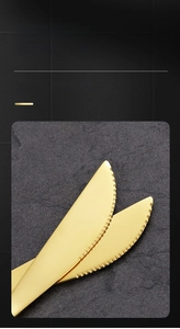 Close-up of golden stainless steel steak knife with serrated blade on stone surface