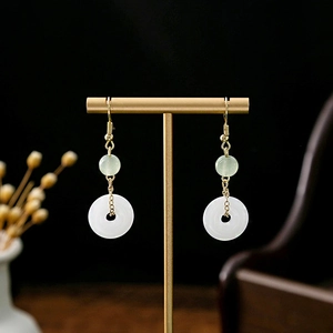 Detail of Chinese style long tassel earrings with green bead and white jade donut