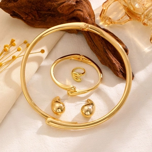 Detailed view of chunky gold-plated jewelry set with necklace, bracelet, and ring on fabric