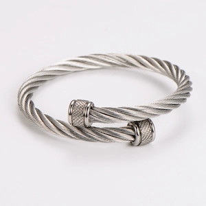Macro detail of silver stainless steel cable bracelet showing woven texture and mesh ends